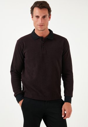 Dark maroon long-sleeve polo shirt with a black collar and three-button placket. Ribbed cuffs and textured fabric. Black pants.