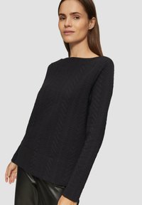 Schwarzer Strickpullover mit strukturierter Fischgrätmuster, langen Ärmeln, rundem Hals und einer lockeren Passform.