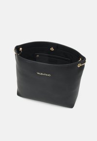 Sac en toile en cuir noir avec une finition texturée, des détails en doré, et un intérieur spacieux comprenant des poches pour l'organisation.