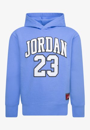 Lyseblå hættetrøje med hvid og sort omrids af teksten "JORDAN 23" og en lille rød Jumpman-logo lap nær kanten.