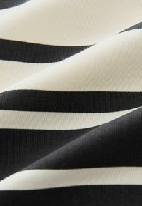 Tissu rayé horizontal noir et blanc avec une texture tricotée lisse, présenté en gros plan avec de doux plis.