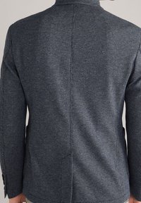 Dark blue blazer with a textured pattern, single vent at the back, and slim-fit design. Features two buttons on each cuff.