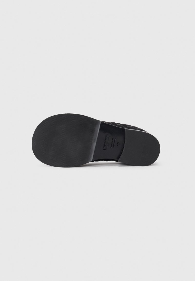 Zwarte rubberen zool met een gladde oppervlakte, ronde hak en geperste merklogo. Voorzien van tekstuurranden voor grip.