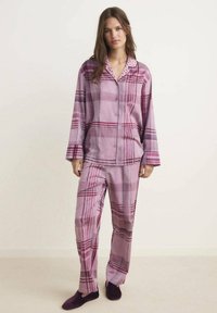 Conjunto de pijama de cuadros morados que incluye una camisa de botón con un cuello de lunares y pantalones holgados a juego, fabricado en un tejido suave.