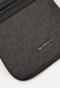 Juodas tekstūruotas užtrauktukas su subtiliu raštu, kuriame yra sidabrinė "Valentino" logotipas. Pagaminta iš tvirto sintetinės medžiagos.