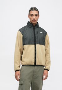 Černá a hnědá zateplená bunda na zip z fleecu a syntetického materiálu, s vysokým límcem, přední kapsou na zip a logem Nike na hrudi.