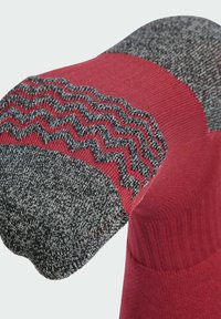 Červená a šedá ponožka s cik-cak vzorem a texturovanou tmavě šedou špičkou, která vykazuje žebrovaný design po celé délce.