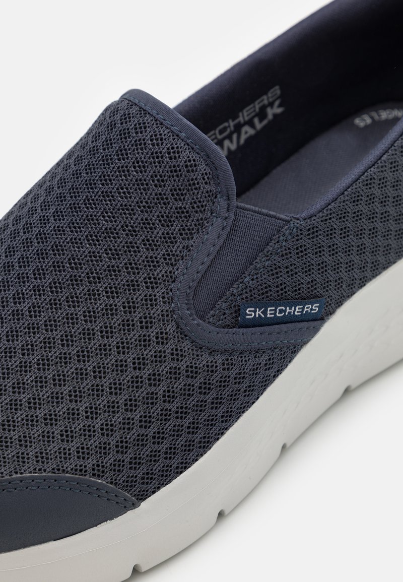 Marineblauwe instapsneaker met een bovenwerk van mesh, gewatteerde kraag en witte zool met textuurdetail. Mer logo aan de zijkant.