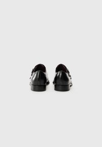 Schwarze Lederschuhe mit runder Zehenform, doppelter Schnallenhardware und glatter Textur. Mit einer robusten Gummisohle und weinrotem Innenfutter.