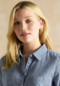 Blauw-witte geruite overhemden met een kraag, voorzien van knopen en een borstzak. De stof lijkt lichtgewicht met een soepele textuur.