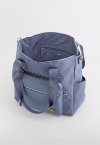 Blå canvas tote-väska med dubbla handtag, dragkedjestängda fack och en mindre framficka med dragkedja och logotypdetalj.