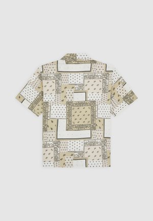 Camicia a maniche corte in tessuto beige con vari motivi geometrici, tra cui disegni floreali e a puntini, disposti a patchwork.