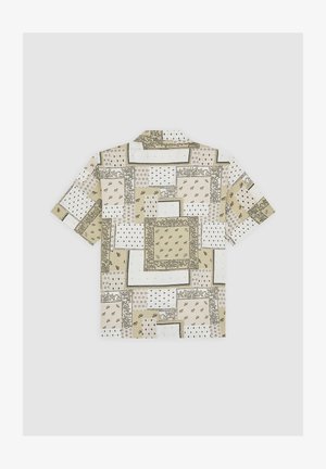 Camicia a maniche corte in tessuto beige con vari motivi geometrici, tra cui disegni floreali e a puntini, disposti a patchwork.