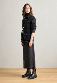 Czarna dżinsowa kurtka z zapięciem na guziki, dwoma kieszeniami na piersi i paskiem. Uzupełniona długą czarną spódnicą dżinsową oraz czarnymi botkami za kostkę z akcentami w panterkę.
