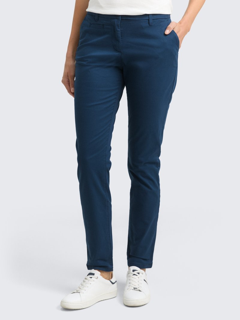 Marineblauwe chinos met een slim fit, gemaakt van lichtgewicht stof. Voorzien van voorzakken en een soepele textuur, gecombineerd met witte sneakers.