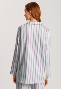 Lichtblauw gestreept pyjama-top met lange mouwen en een notch-kraag. Kenmerkt zich door dunne rode en paarse verticale strepen. Glad stoftextuur.