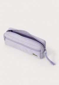 Trousse violette avec fermeture éclair, fabriquée en tissu texturé, dotée d'un petit logo brodé et d'une languette sur le côté pour un accès facile.
