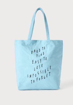 Sac cabas bleu clair avec deux poignées et texte noir indiquant "Hard to find easy to lose impossible to forget" à l'avant.
