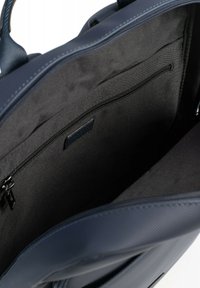 Marineblauwe neplederen tas met een gestructureerd exterieur, bovenste ritssluiting en een ruime zwarte stoffen interieur met een ritsvak.
