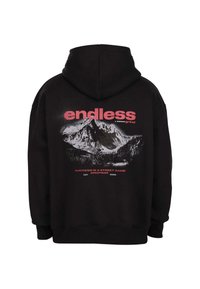 Schwarzer Hoodie mit einem Berg-Graphic und den Worten "endloser Grind" und "Erfolg ist ein Straßenspiel" in pink- und weißer Schrift auf der Rückseite.