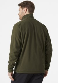 Giacca in pile verde con colletto alto, maniche lunghe e un tessuto testurizzato. Include un orlo discreto e dettagli sulle cuciture laterali.
