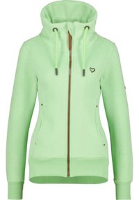 Sudadera con cremallera de color verde claro, hecha de una tela suave. Presenta un cuello alto, cordones y un logo en forma de corazón. Incluye bolsillos laterales y puños acanalados.