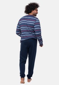 Maglietta a maniche lunghe a righe blu, rossa e grigia; abbinata a pantaloni navy a tinta unita. Tessuto morbido, vestibilità rilassata e cintura elastica.