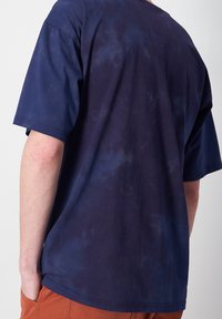 Camiseta de manga corta azul marino con un ajuste relajado, hecha de una tela suave que presenta un sutil estampado de tie-dye.