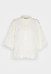 Blouse blanche à manches courtes avec col mandarin, patte de boutonnage devant et détail en dentelle ajourée sur les manches et l’ourlet avec bords festonnés.