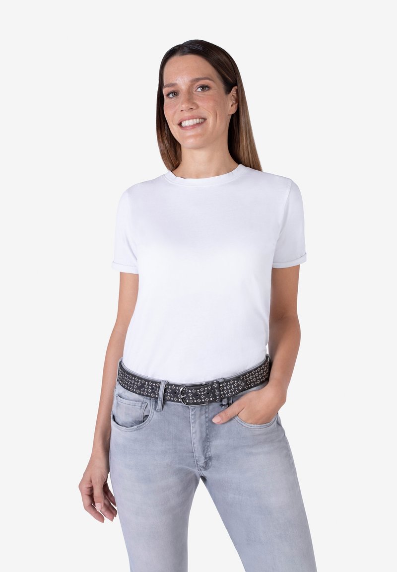 T-shirt bianca in cotone con scollo rotondo, maniche corte, abbinata a jeans grigi chiari e una cintura nera borchiata. Design semplice e casual.