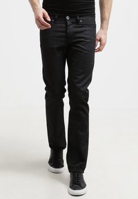Jeans de mezclilla negra de corte ajustado, con cinco bolsillos y cierre de botón, que presentan una textura sutil y sin adornos visibles.