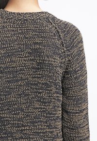 Stickad tröja med ett strukturerat mönster i m örkblå och tan-färger. Rund halsringning och långa ärmar med en avslappnad passform.
