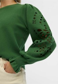 Pull vert à manches bouffantes avec découpes florales et poignets côtelés ; tissu en maille texturée ; silhouette slim.