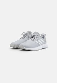 Harmaat urheilujalkineet, joissa on teksturoitu päällinen, valkoinen kolmiraidallinen muotoilu, pyöreät nauhat ja pehmustettu nilkkakappale. Urheilullinen pohja, joka tarjoaa pidon.