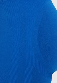 Blauwe gebreide stof met een mix van textuurpatronen, waaronder ribbelige en gladde secties, in verschillende tinten blauw.