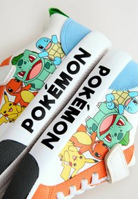 Sneaker mit mehrfarbigen Pokémon-Charakteren auf einer weißen und orangefarbenen Basis, mit blauen Akzenten und strukturiertem schwarzen Gummisohle.