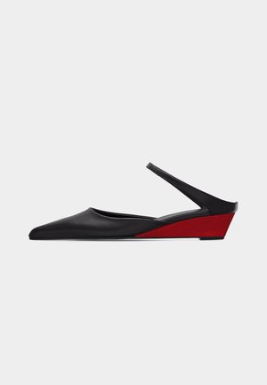 Chaussure noire à bout pointu, bride arrière, avec un talon compensé rouge bas et une fine bride de cheville sur un fond uni.