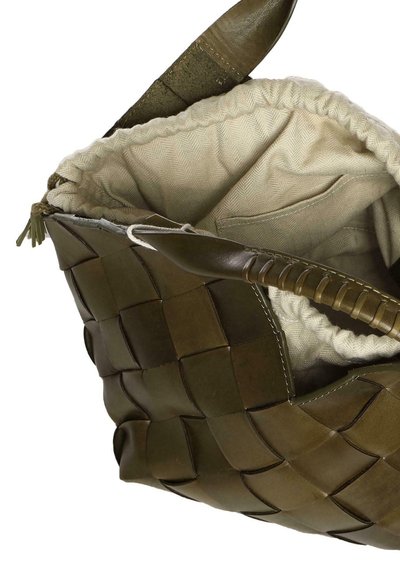 Bolso de mano tejido en cuero verde oliva con forro interior de tela crema y un bolsillo interno, mostrado con la parte superior abierta.