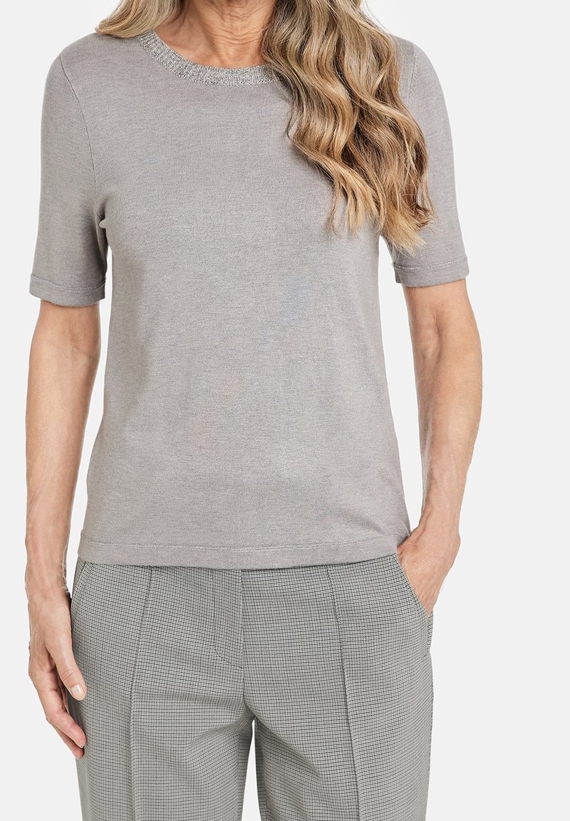 Šedý top s krátkým rukávem a kulatým výstřihem, který se vyznačuje texturovanými detaily, vyrobený z měkkého materiálu. Kombinovaný s kostkovanými kalhotami.