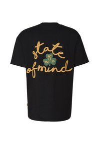 Musta puuvillainen t-paita, jossa suuri keltainen kaunokirjoitusteksti "state of mind" ja vihreä apilan kuva takana. Lyhyet hihat, väljä istuvuus.