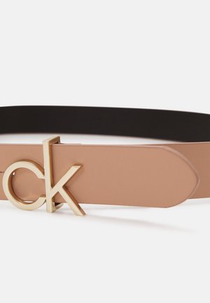 Ceinture en cuir fauve avec une boucle dorée "ck" et une doublure intérieure noire, affichée sur fond blanc.