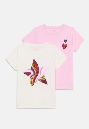 Two T-shirts: one white with a multi-colored star design featuring glitter, and one pink with three glittering hearts in varying sizes.