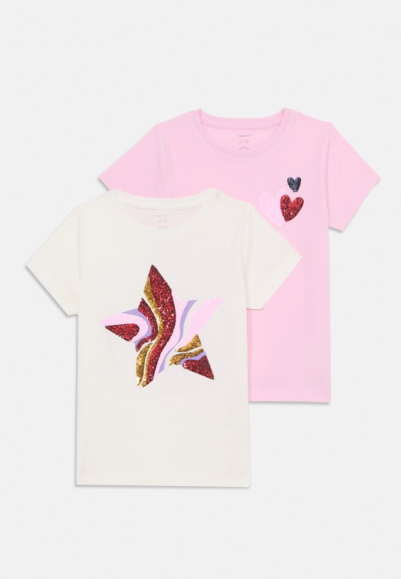 Dos camisetas: una blanca con un diseño de estrellas multicolores que incluye purpurina, y una rosa con tres corazones brillantes de diferentes tamaños.