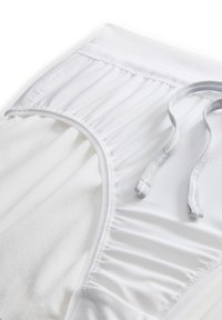 Baltos sportinės kelnės su tekstūruotu juosmens diržu, raukšlėtu audiniu ir reguliuojama raišteliu. Minkšta medžiaga su lygiais detalėmis.