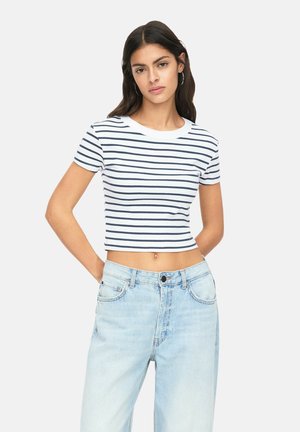 Crop top blanc avec des rayures horizontales navy, col rond, manches courtes, associé à un jean taille haute bleu clair.