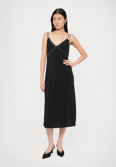 Czarna satynowa sukienka na ramiączkach z dekoltem w serek, ozdobiona dekoracyjnymi koralikami na gorsecie i o gładkiej, płynącej sylwetce.