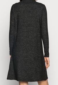 Robe à manches longues en tissu gris foncé, avec une coupe décontractée et un ourlet légèrement évasé. Tricot texturé avec un motif subtil.