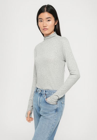 Gray long-sleeve turtleneck top in a soft, stretchable fabric, paired with light blue high-waisted jeans featuring front pockets.