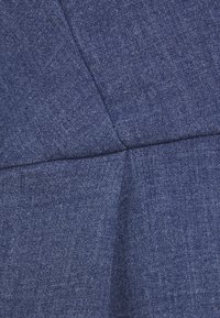 Denimtyg i djupt blått, med en texturerad väv som har synliga sömmar och en lätt lyster, strukturerat i en figurnära form.