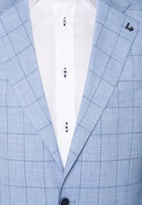 Light blue checked blazer with a notched lapel, paired with a white dress shirt featuring blue button accents and textured fabric.